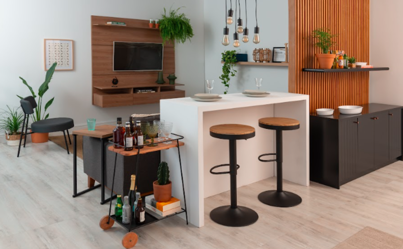 decoração de barzinho em casa com banquetas, bancada, carrinho bar na sala de estar com rack e diversos itens decorativos