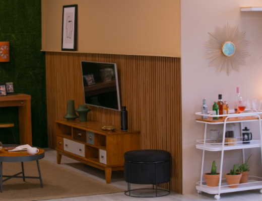 home bar na sala de estar com carrinho bar pequeno, com diversas bebidas e taças