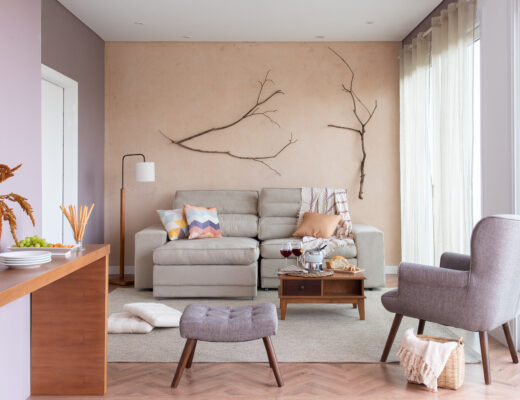 decoração de outono com flores secas, sofá cinza, itens decorativos aconchegantes como almofadas e mantas, entre outros
