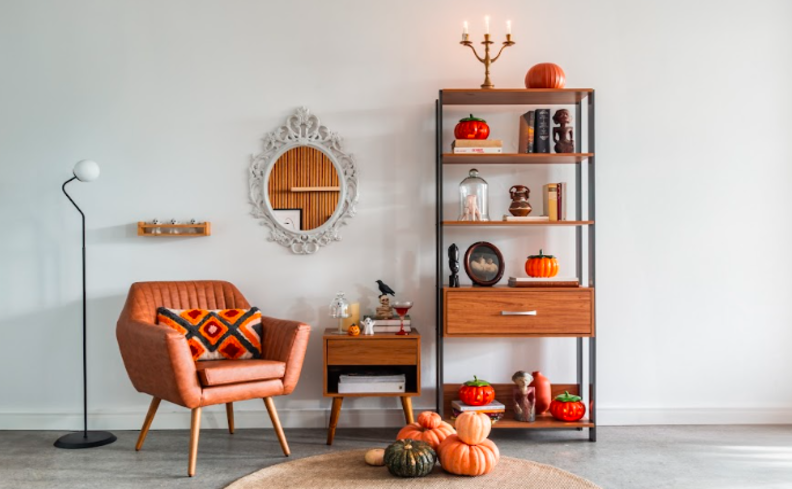 decoração de outono com tons terrosos, poltrona marrom, luminária de chão, estante, tapete e diversos itens de decoração