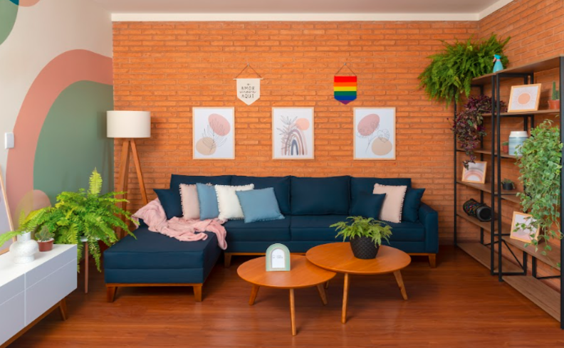 sala com sofá de canto azul, mesa de centro, quadros e itens de decoração para ter uma sala aconchegante