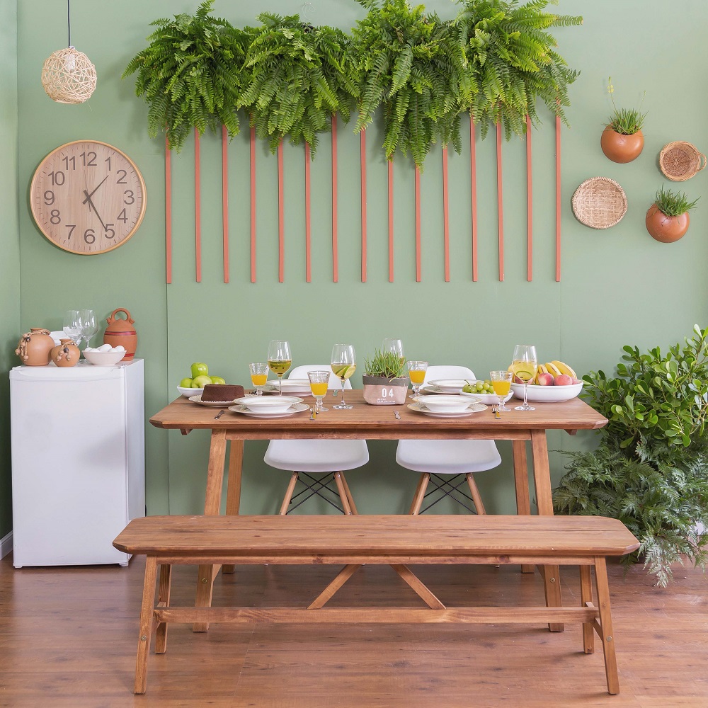 Sala de jantar com parede e plantas em tons de verde, mesa posta no meio combinada com um banco e duas cadeiras de jantar