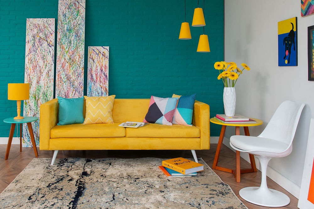 Sala de estar com parede verde ao fundo e objetos amarelos em destaque