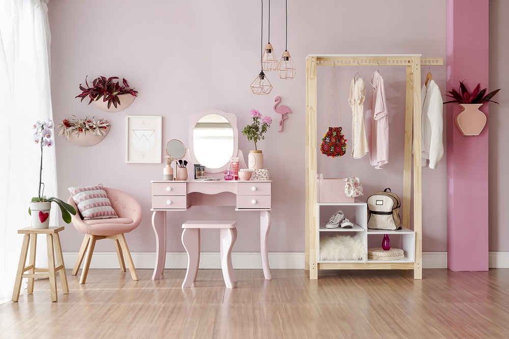 Quarto decorado com tons de rosa em que a cor aparece na parede, decorações e móveis.