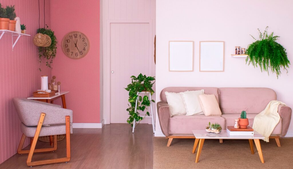 decoração romântica com sofá fixo rosa, poltrona, plantas e mesa de centro