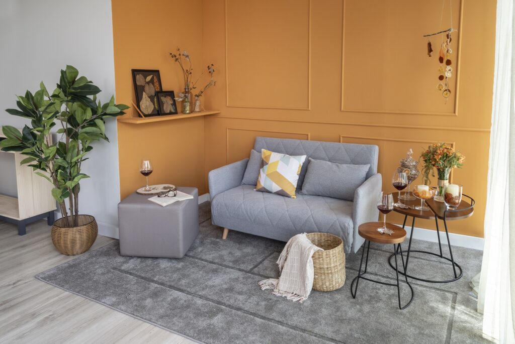 entre os modelos de sofá para sala, um modelo pequeno fixo de dois lugares, com puff, mesas laterais e diversos itens de decoração
