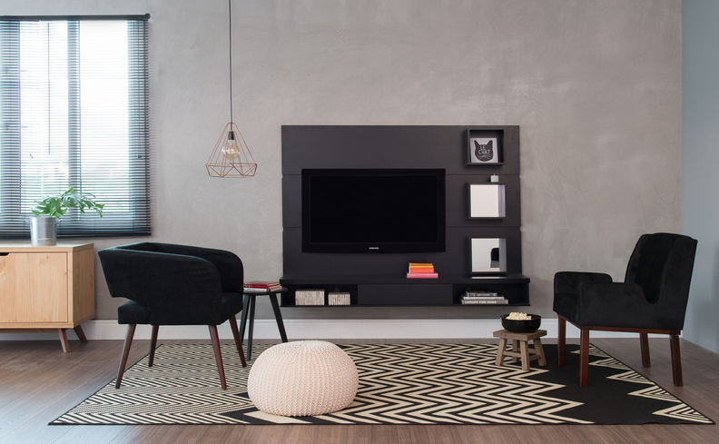 sala de estar moderna com rack, poltronas, tapete, puff e outros elementos decorativos em tonalidades neutras