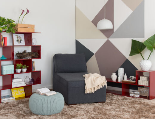 ambiente com estante para sala de estar, sofá, puffes, mesa lateral, tapete e diversos itens decorativos