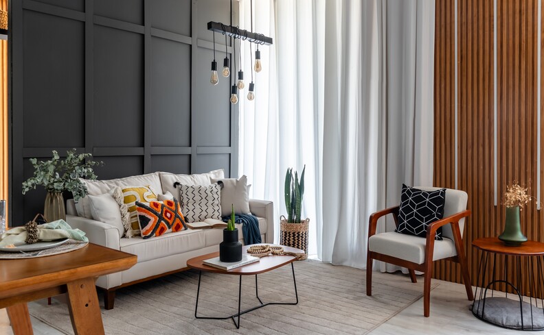 sofá branco moderno na sala de estar com poltrona, mesa lateral, lustre, almofadas e outros itens