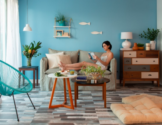 sala aconchegante com um sofá, almofadas, mesas de centro com itens decorativos, estante e outros itens