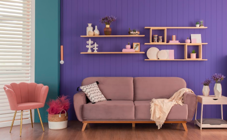 sala aconchegante pequena com parede roxa e verde, sofá fixo 2 lugares, poltrona, almofadas, manta para sofá e outros itens de decoração