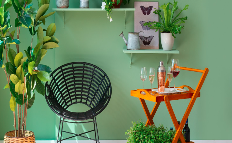 barzinho em casa pequeno com poltrona, carrinho bar, taças e diversos itens de decoração