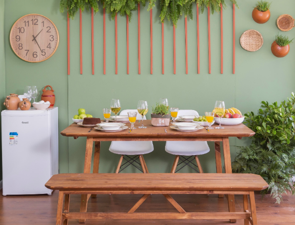 ambiente pronto para aproveitar o dia do Churrasco com uma mesa grande, bancos e duas cadeiras, além de um frigobar e itens para servir