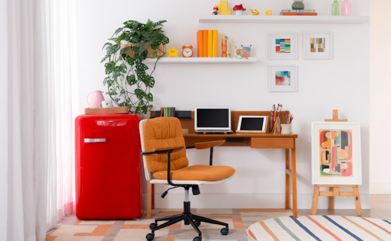 cantinho de home office na sala com cadeira, frigobar, escrivaninha e prateleiras com itens decorativos