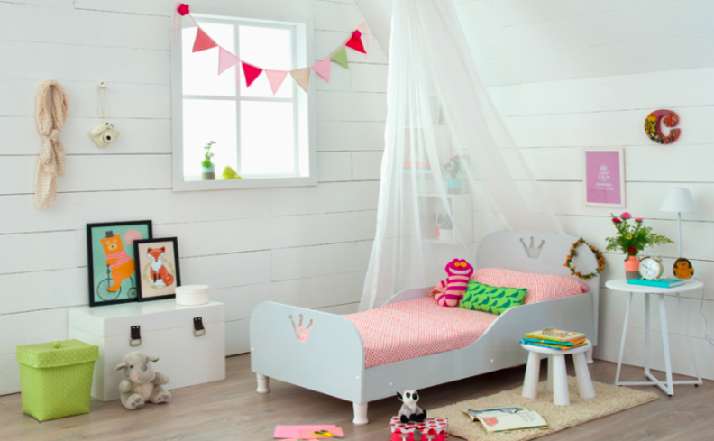 quarto de criança com decoração geek com quadros, pelúcias, almofadas e diversos outros itens decorativos