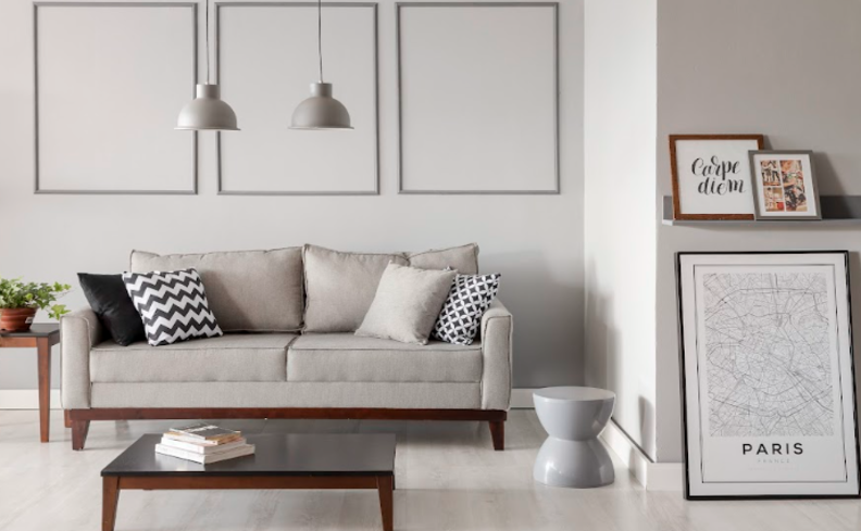 estilo minimalista decoração com sofá cinza, almofadas em tons neutros, quadros e uma mesa de centro