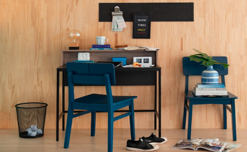 home office na sala de apartamento com escrivaninha, cadeiras e itens de papelaria