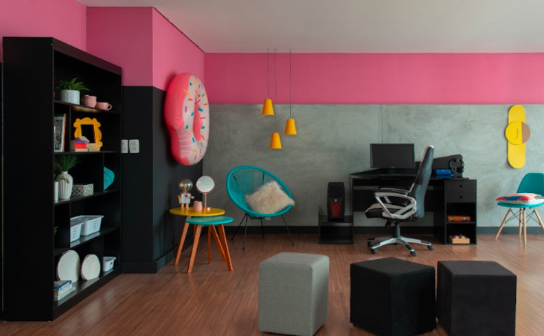 home office na sala de estar com cadeira, estante grande, escrivaninha e itens decorativos