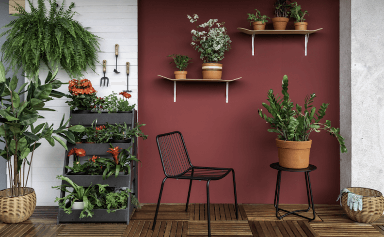 mesa para varanda pequena com vaso em cima, cadeira, estante e diversas plantas em prateleiras para decorar