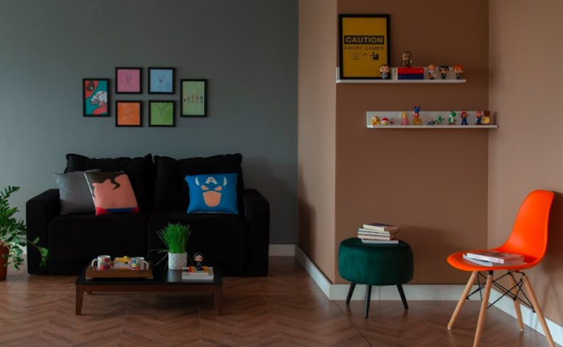 decoração com quadros geek na sala de estar com sofá, almofadas, cadeira, puff e diversos itens decorativos