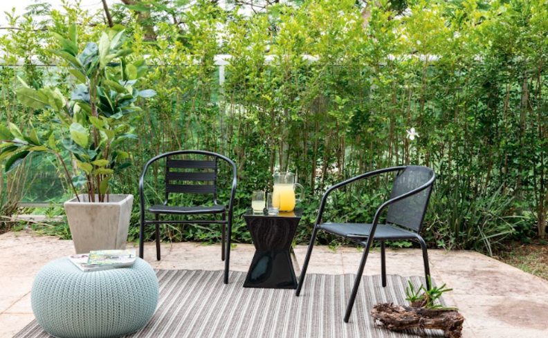 varanda pequena em casa com duas cadeiras, puff, mesa de apoio e diversas plantas para decorar o cômodo