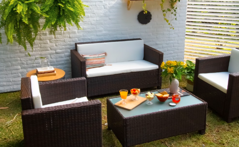 dicas de churrasco em casa para preparar um ambiente na área externa com sofá, poltronas e mesa de apoio.