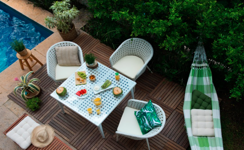 churrasco em casa em uma área externa com mesa, cadeiras, rede e um kit de facas para churrasco para facilitar o preparo.