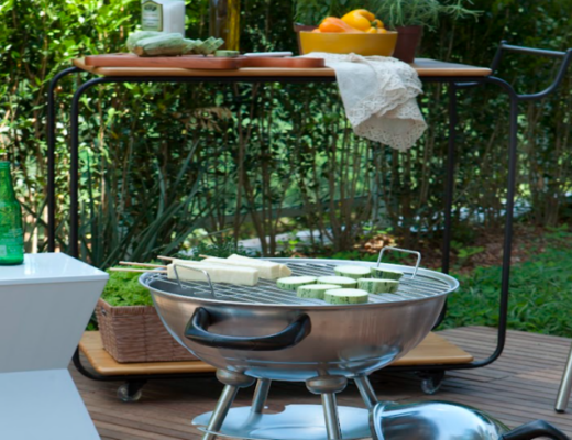 churrasco em casa em uma área externa com churrasqueira, mesa, bancos e itens indispensáveis para esse evento
