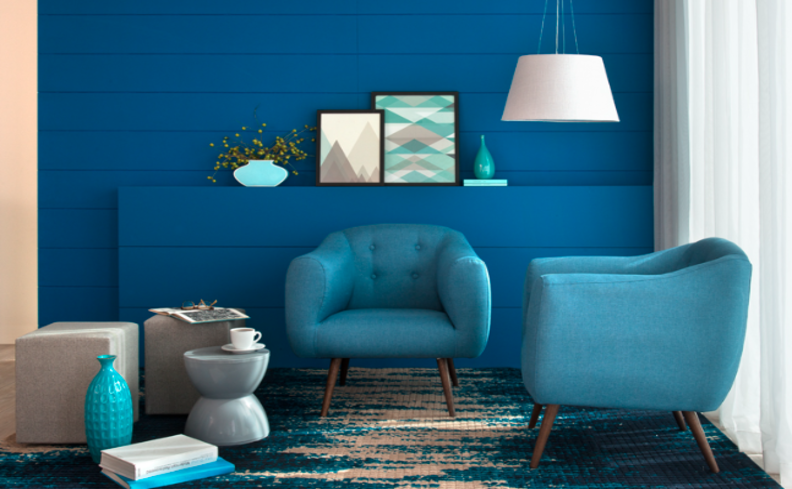 sala com tons de azul escuro na parede e poltronas em tons de azul mais claro, além de itens decorativos e um tapete