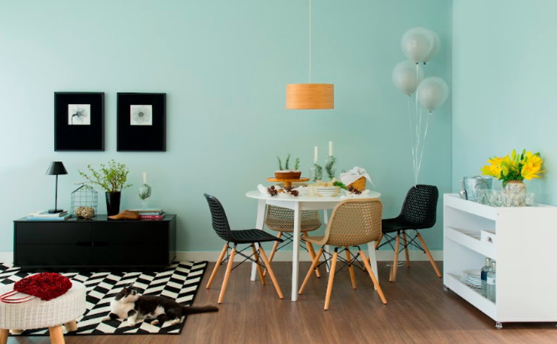 tons de azul claro na parede em um ambiente de sala de jantar com mesa, cadeiras, buffets e itens decorativos.