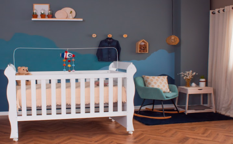 tons de azul para parede de quarto de bebê, além de berço, poltrona e mesa de apoio.