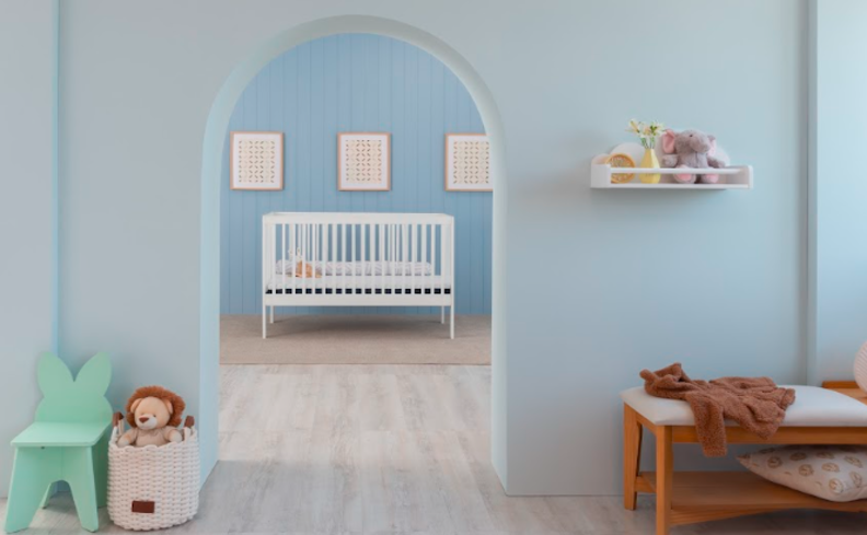 tons de azul turquesa na parede de um quarto de bebê, além de berço, quadros decorativos, mesa de apoio e uma cadeira infantil.