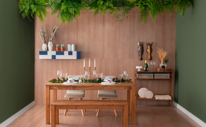mesa de jantar 4 lugares retangular em madeira, com mesa posta completa, prateleiras com itens decorativos e um carrinho bar no canto.