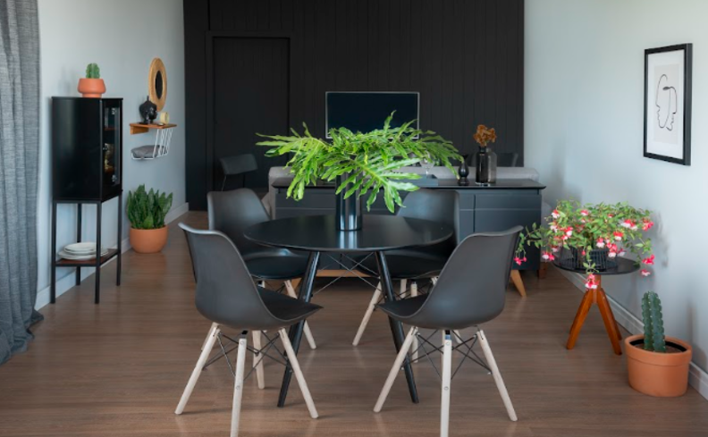 mesa de jantar pequena redonda preta com quatro cadeiras pretas em uma sala de jantar integrada com a sala de estar