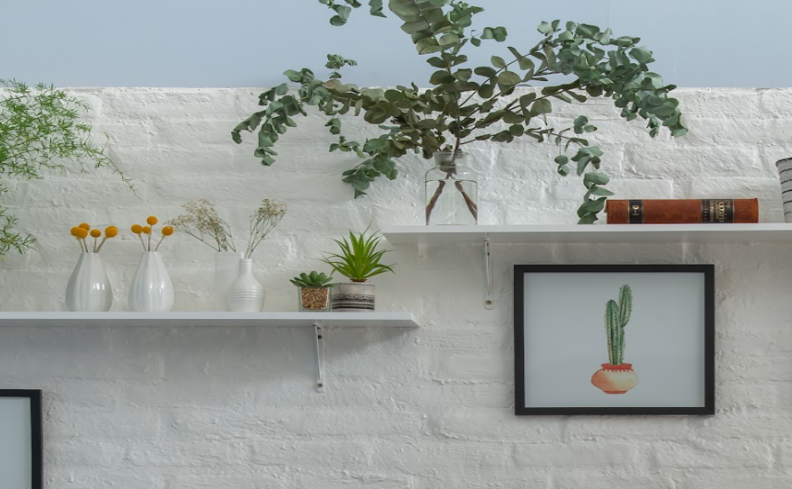 plantas artificiais para banheiro em prateleiras, além de vasos e quadros decorativos.