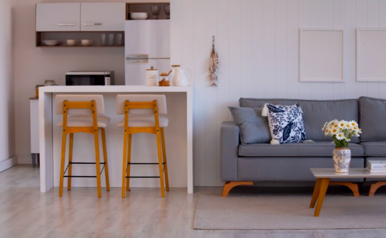 como manter a casa limpa e organizada com sala de estar integrada com a cozinha, com balcão, banquetas, sofá, mesa de centro e itens decorativos.