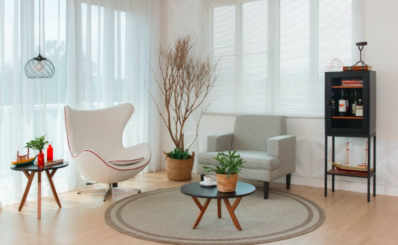 como organizar a casa em uma sala de estar com duas poltronas, tapete, mesa de centro e itens decorativos com plantas.