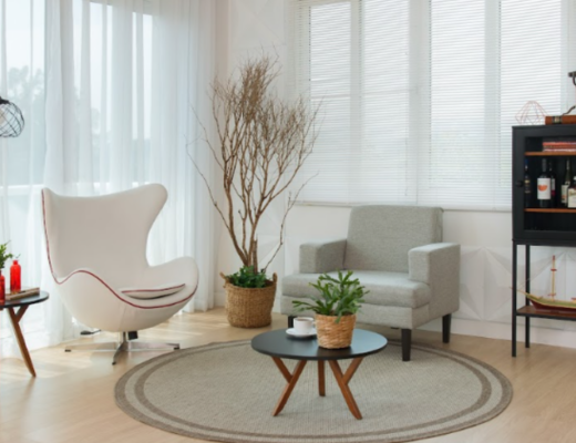 tipos de poltronas para sala de estar, com tapte, mesa lateral e de centro, estante e diversos itens decorativos.
