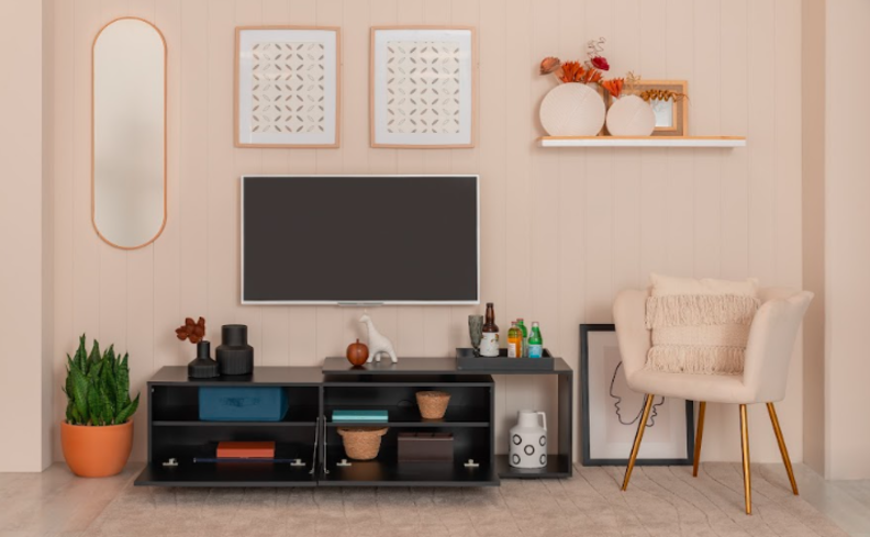 sala de estar organizada com rack, televisão, poltrona, prateleiras e diversos objetos de decoração.
