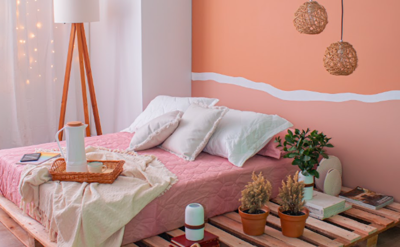 decoração de primavera no quarto de casal em tons de rosa pastel nas paredes e na roupa de cama, além de plantas para decorar e levar natureza ao ambiente.