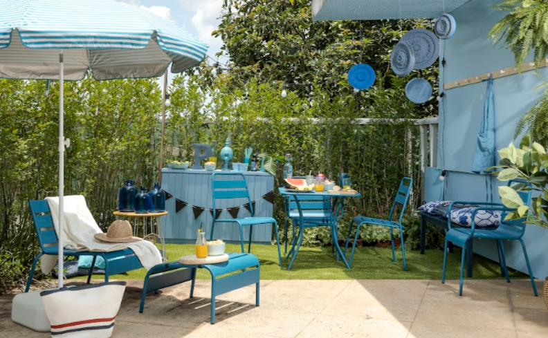 jardim vertical artificial na área externa com poltronas, ombrelone, cadeiras e mesa.
