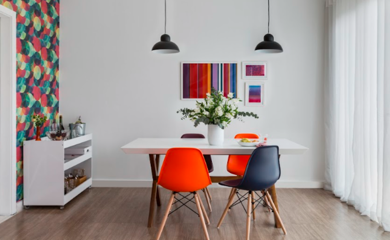 cadeiras em tons de laranja em uma sala de jantar com mesa, quatro cadeiras, buffet e itens decorativos.