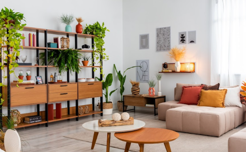 decoração aesthetic da sala de estar com prateleira vazada, diversas plantas, sofá baixo e mesas de centro, além de almofadas e quadros decorativos.