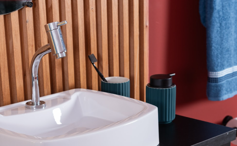 banheiro pequeno com a bancada com torneira, cuba e itens de organização como porta sabonete líquido e porta escovada de dente.