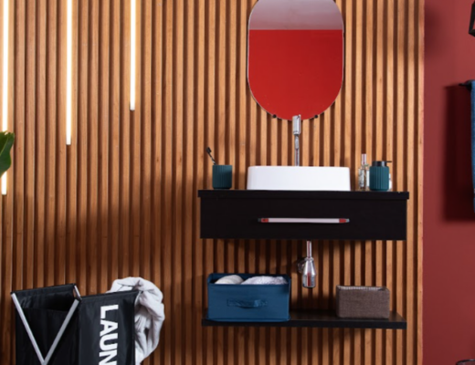 decoração de banheiro pequeno com gabinete, espelho, prateleiras, itens decorativos e funcionais, além de cesto de roupa suja.