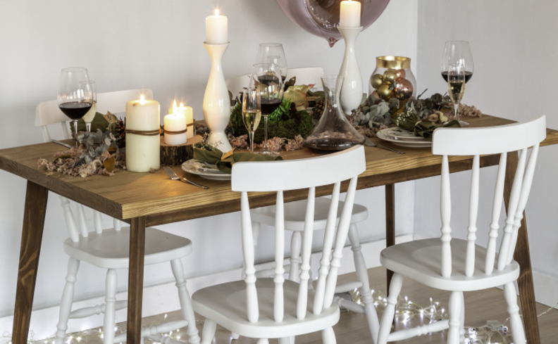 decoração de natal para sala com mesa posta completa em tons de branco e verde, com pratos, talheres, guardanapo de tecido, velas e arranjos natalinos.