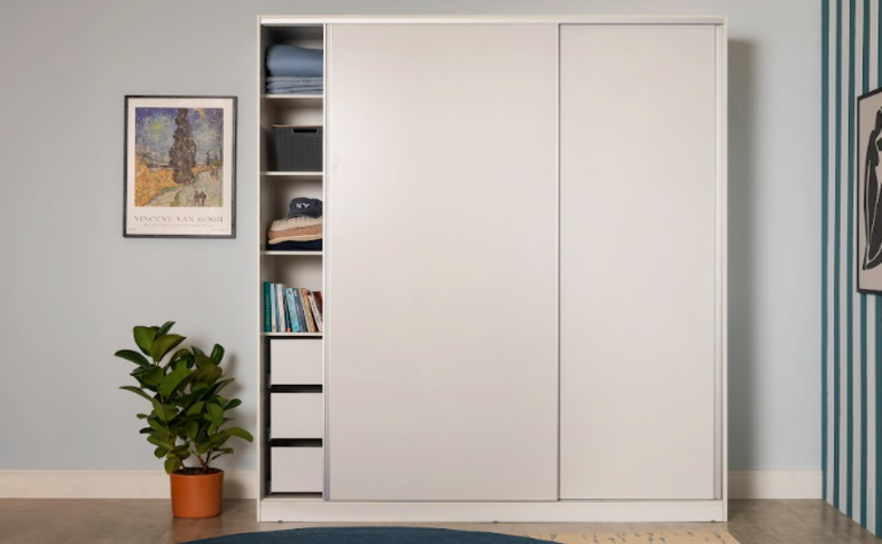 guarda-roupa black friday em um modelo branco com portas de correr, além de vaso com planta e quadros decorativos nas paredes.