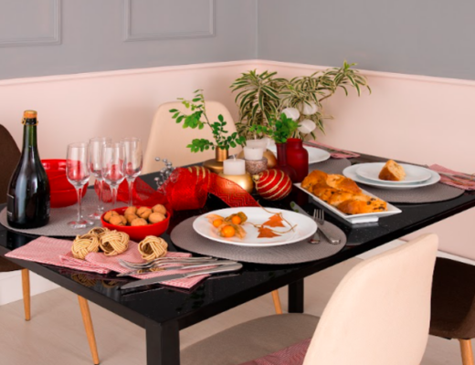 mesa posta de natal com mesa preta, cadeiras brancas e pretas e diversos itens de mesa posta para deixar a ceia de natal completa.