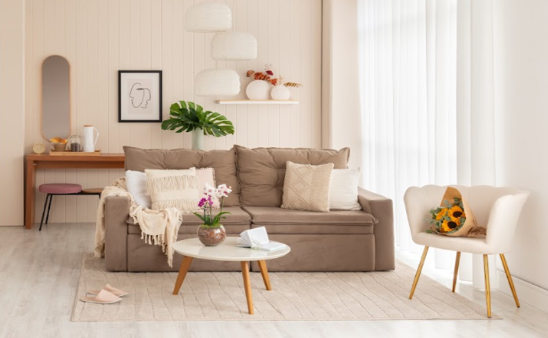 sofá na black friday em um modelo retrátil bege, além de poltrona, mesa de centro, almofadas, manta, rack e itens de decoração na sala de estar.