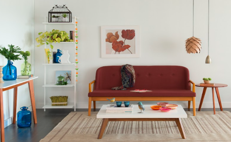 cor de parede de sala neutra com móveis em tons vibrantes como sofá vermelho, itens decorativos azuis e pantas.